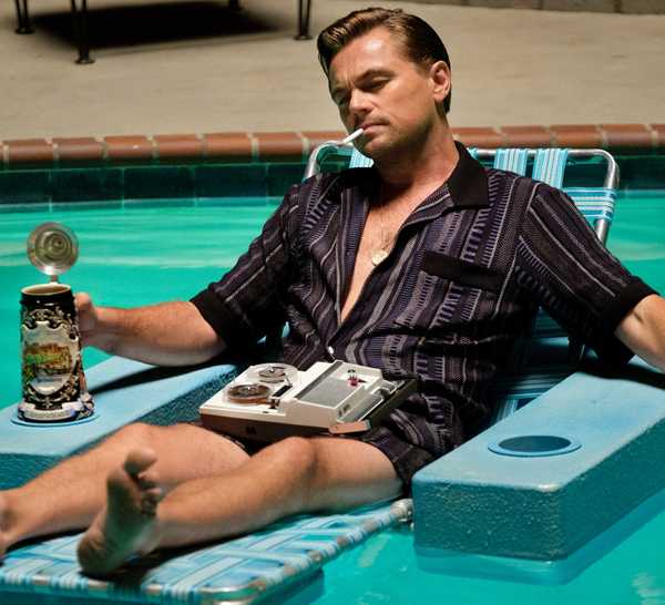 Once Upon A Time In Hollywood still featuring Leonardo DiCaprio in a pool chair, smoking a cigarette with his eyes closed.