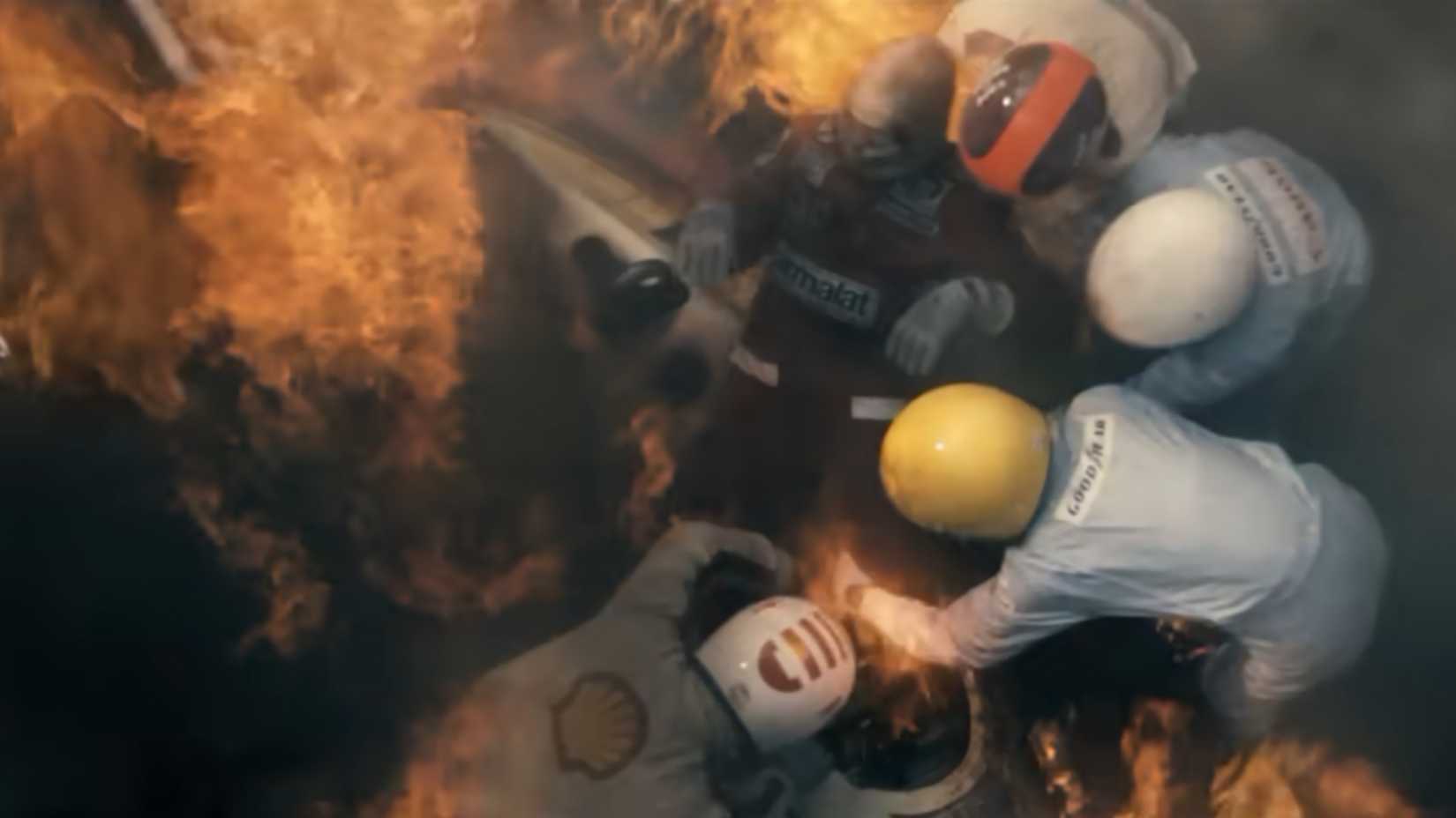 Rescuers pulling Niki Lauda (Daniel Bruhl) out of a burning car in Rush