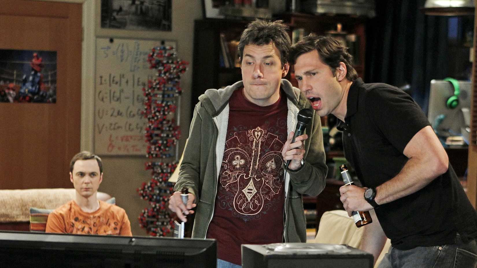 Kripke and Zack singing Karaoke while Sheldon sulks on the couch.