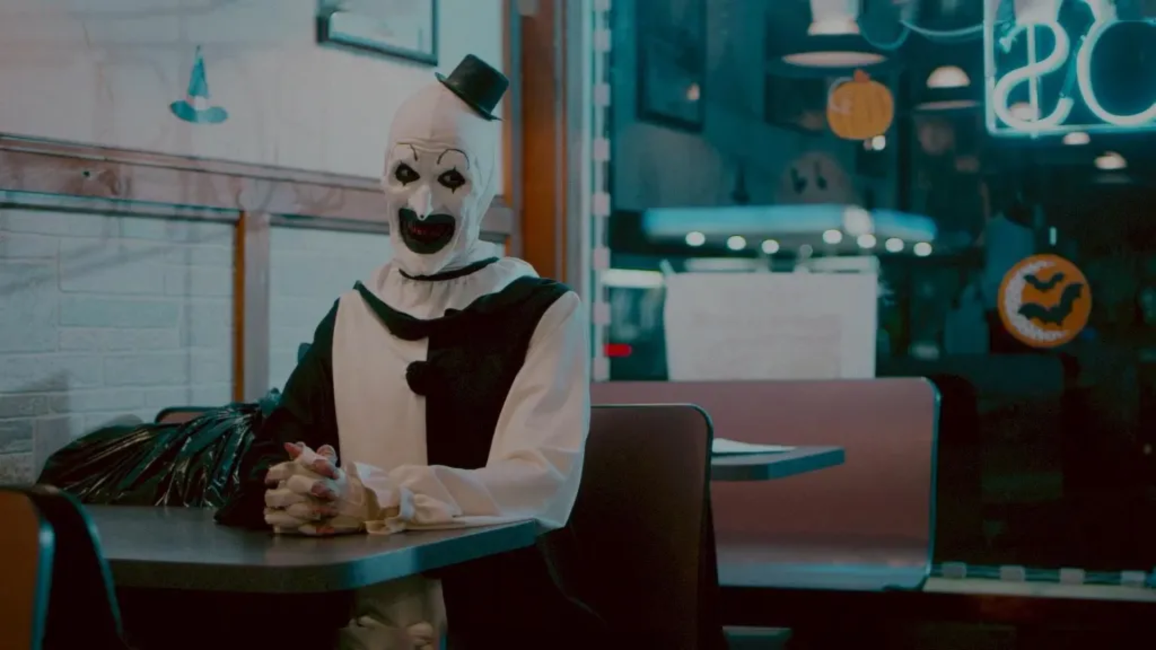 Art the clown grinning in a diner in Terrifier