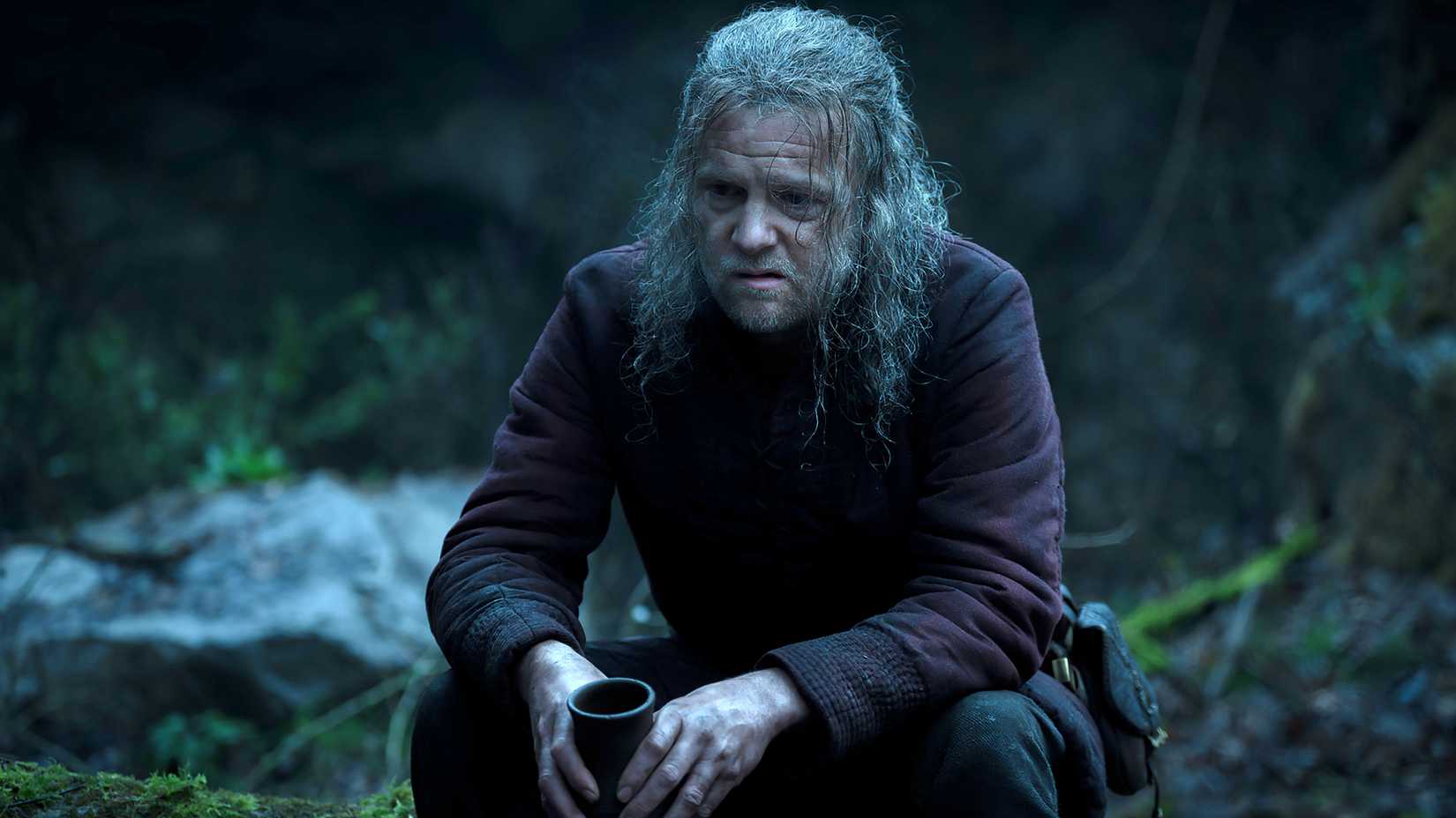 Tom Bennett's Ulf looking somber while sitting with a cup in his hands in House of the Dragon season 3