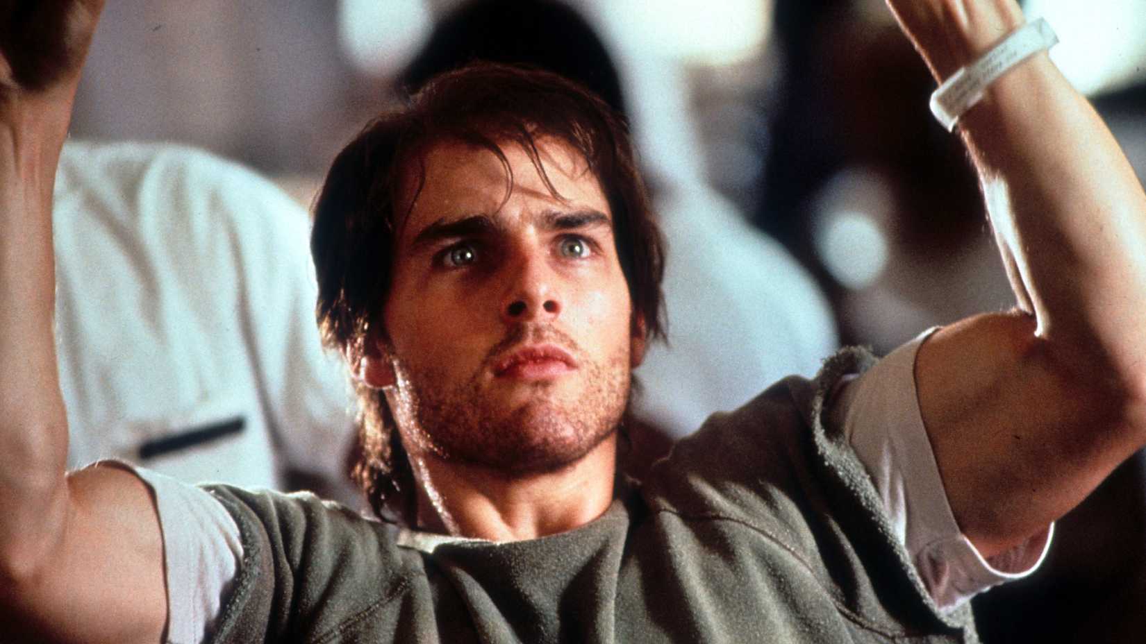 Tom Cruise lifts his arms over his head with his eyes wide in panic in Born on the Fourth of July
