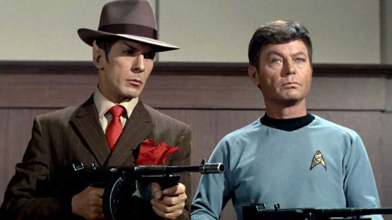 Spock and McCoy holding guns, while Spock is dressed as a gangster
