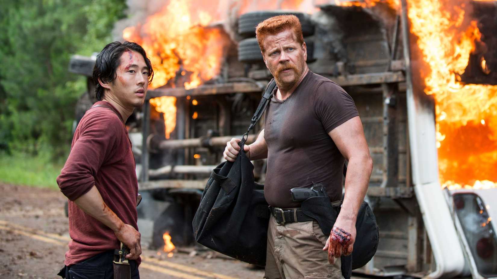 Glenn and Abraham standing in front of a burning vehicle in The Walking Dead 