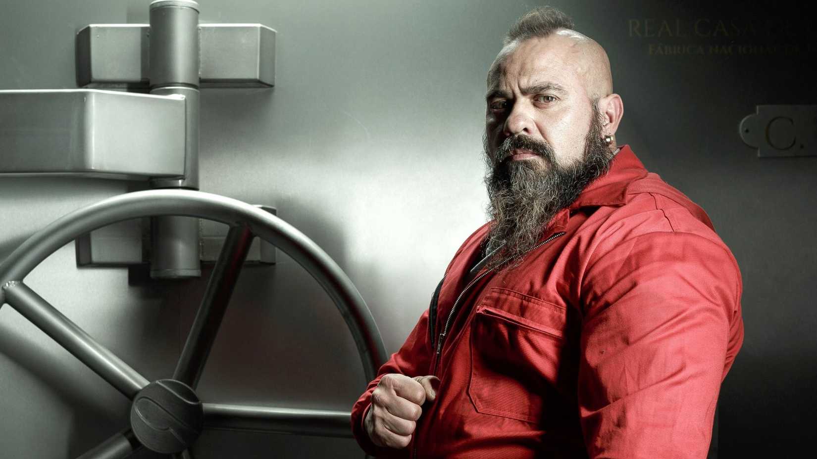 Oslo in a red jumpsuit outside a bank vault