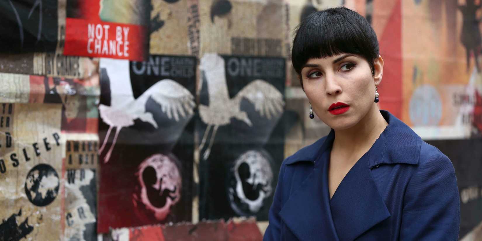 Noomi Rapace in front of posters in What Happened to Monday
