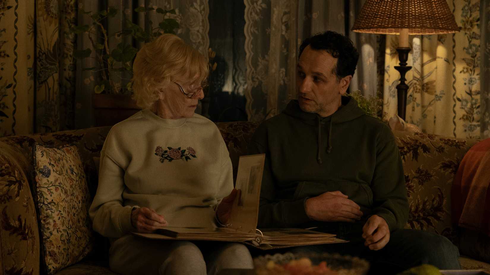 Tom and Ruth looking at a photo album in Widow's Bay season 1