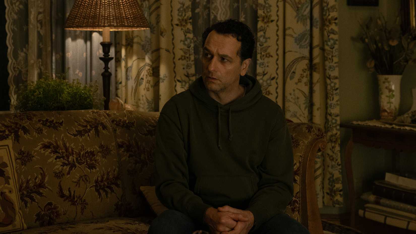 Tom sitting in Ruth's house in Widow's Bay season 1