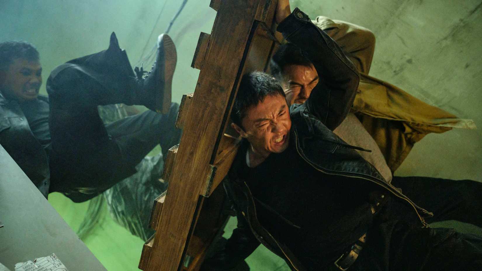 Xie Miao's Wang Wei and Joe Taslim's Navin holding a palette as an enemy kicks against it in The Furious