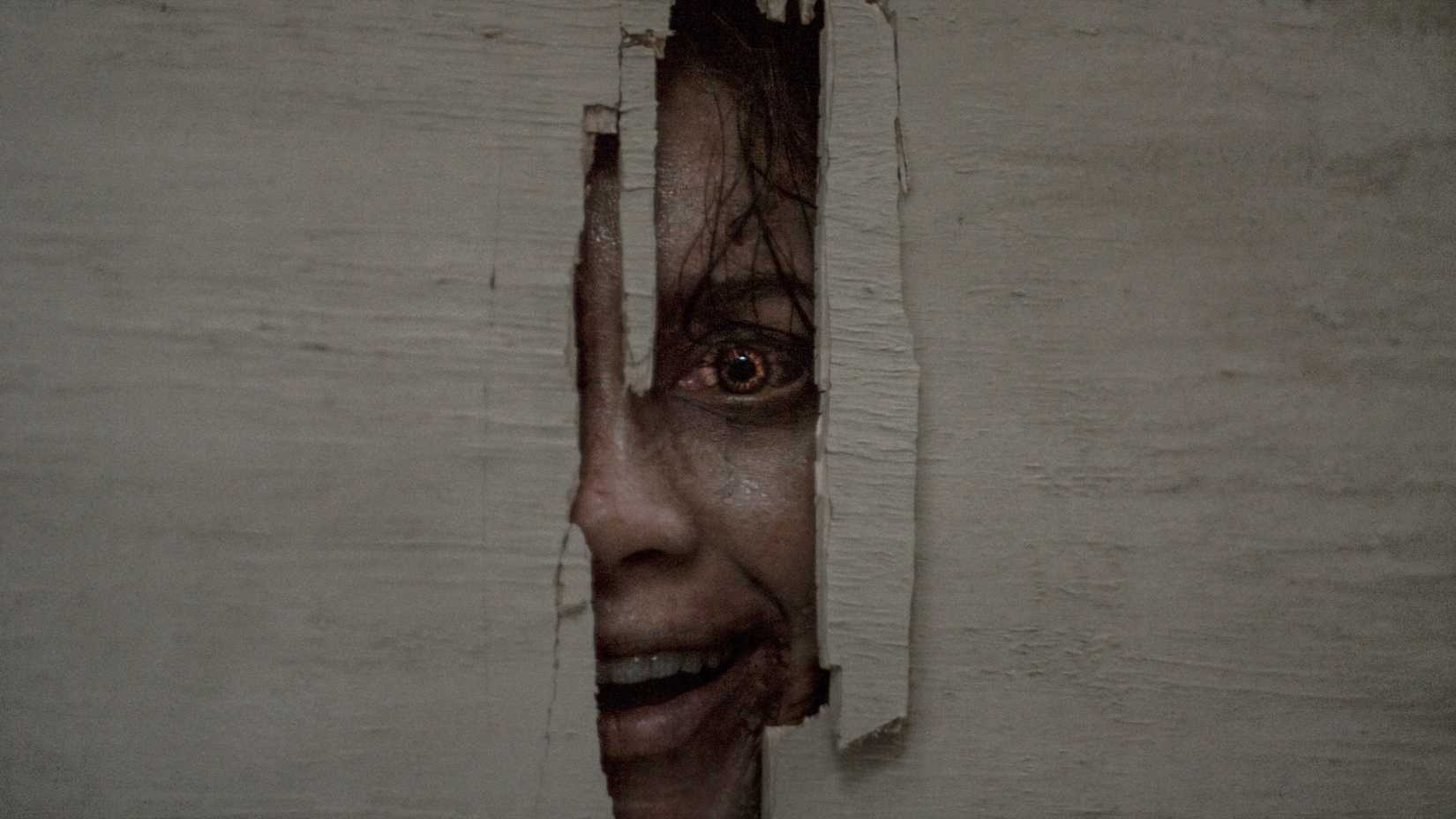 A deadite peeking menacingly through a broken door in Evil Dead Burn