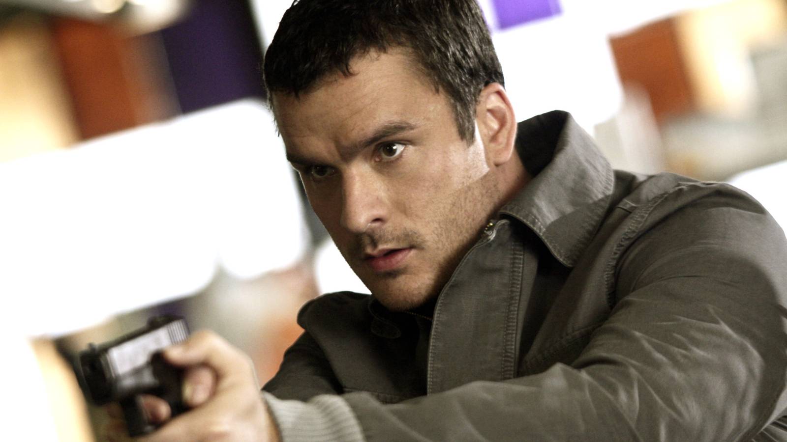 Balthazar Getty looks intense while pointing a gun in a scene from Alias