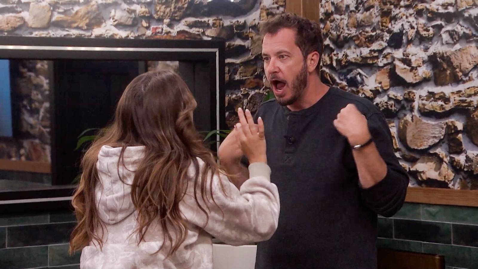 Still of Rick Devens with a shocked expression while Dee Valladares talks with her back to the camera on Big Brother.
