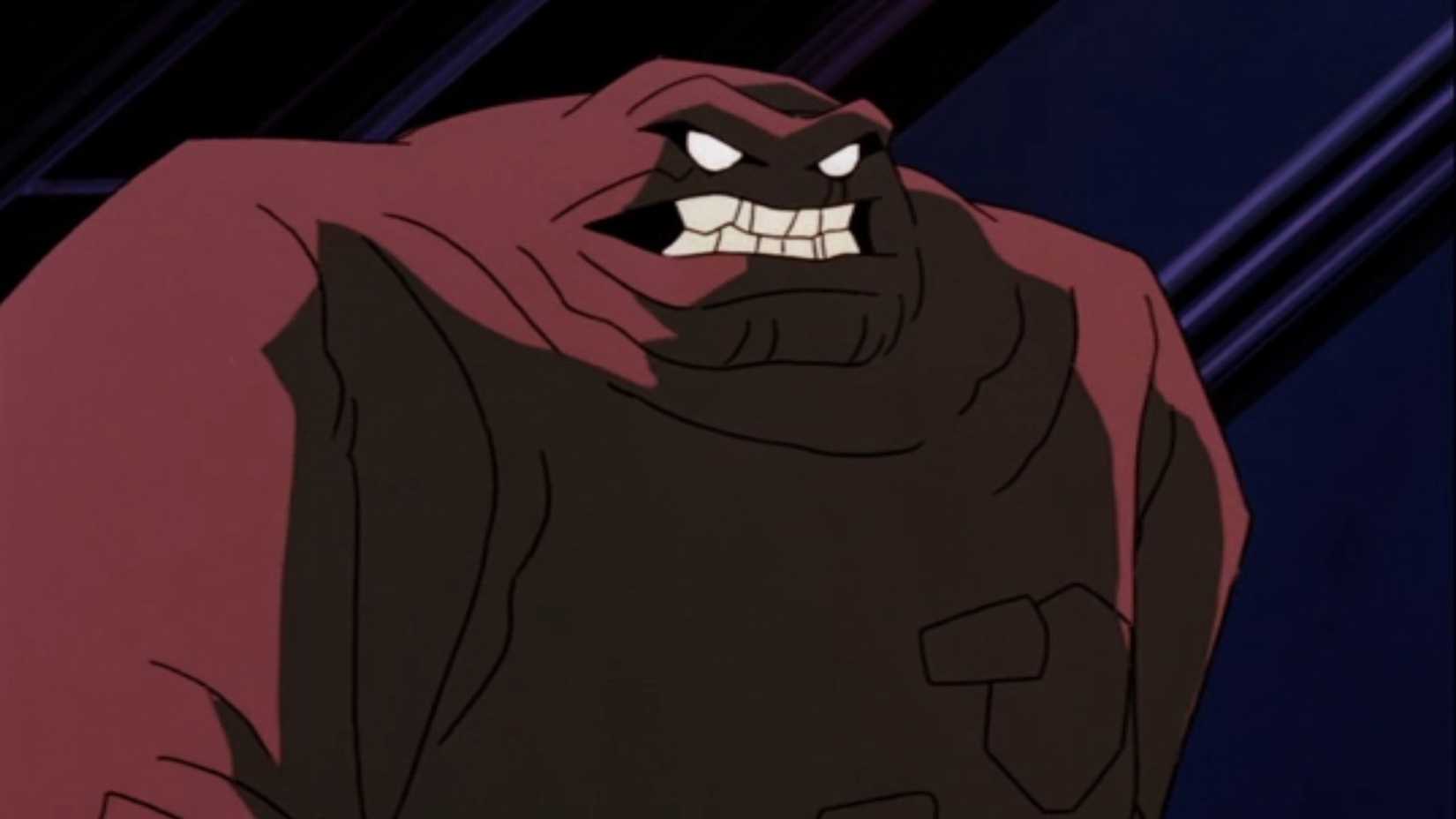 Clayface walking down darkly-lit catwalk
