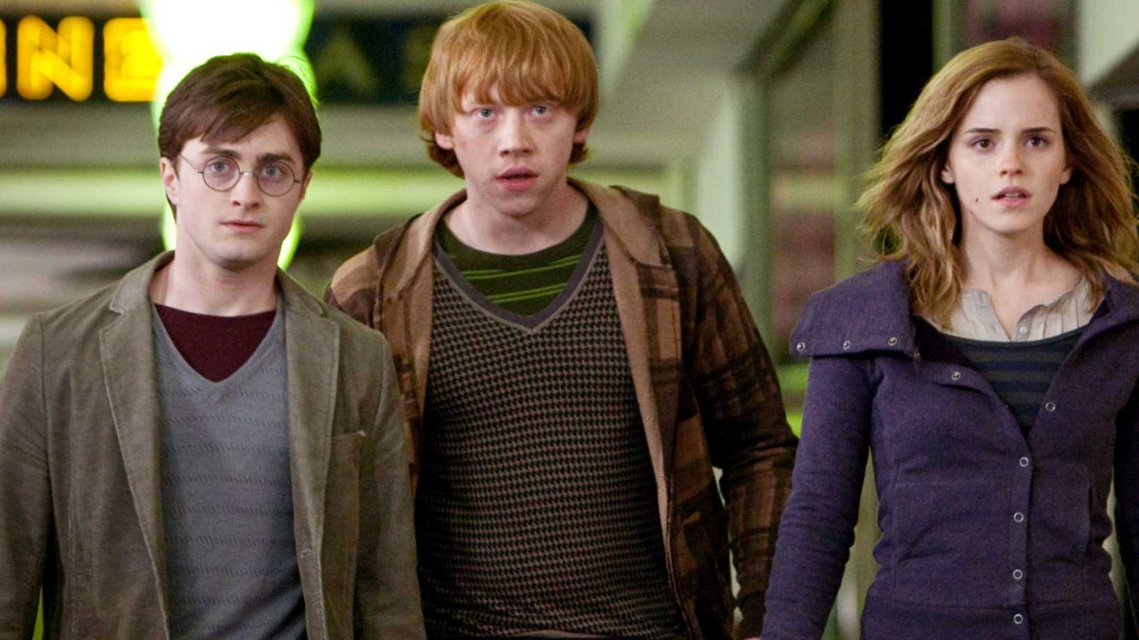 Daniel Radcliffe as Harry Potter, Rupert Grint as Ron Weasley, and Emma Watson as Hermione Granger walking through London in Harry Potter and the Deathly Hallows Part 1