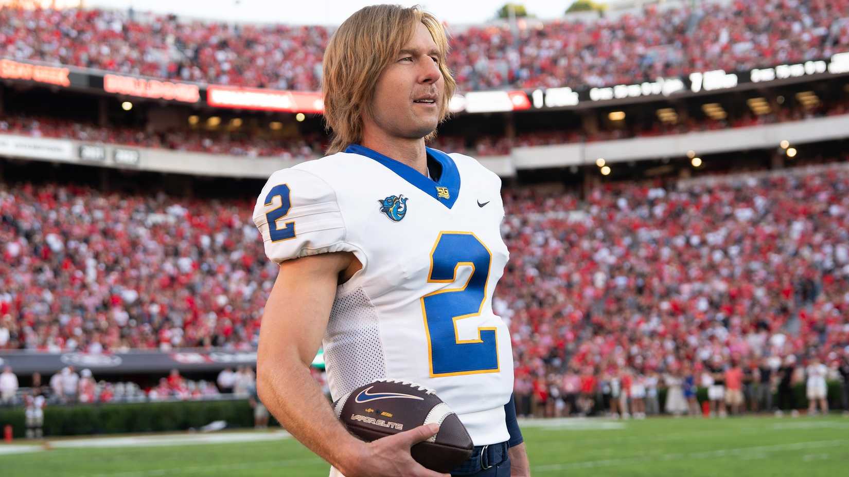 Glen Powell wearing a football uniform and holding a football in Chad Powers season 1