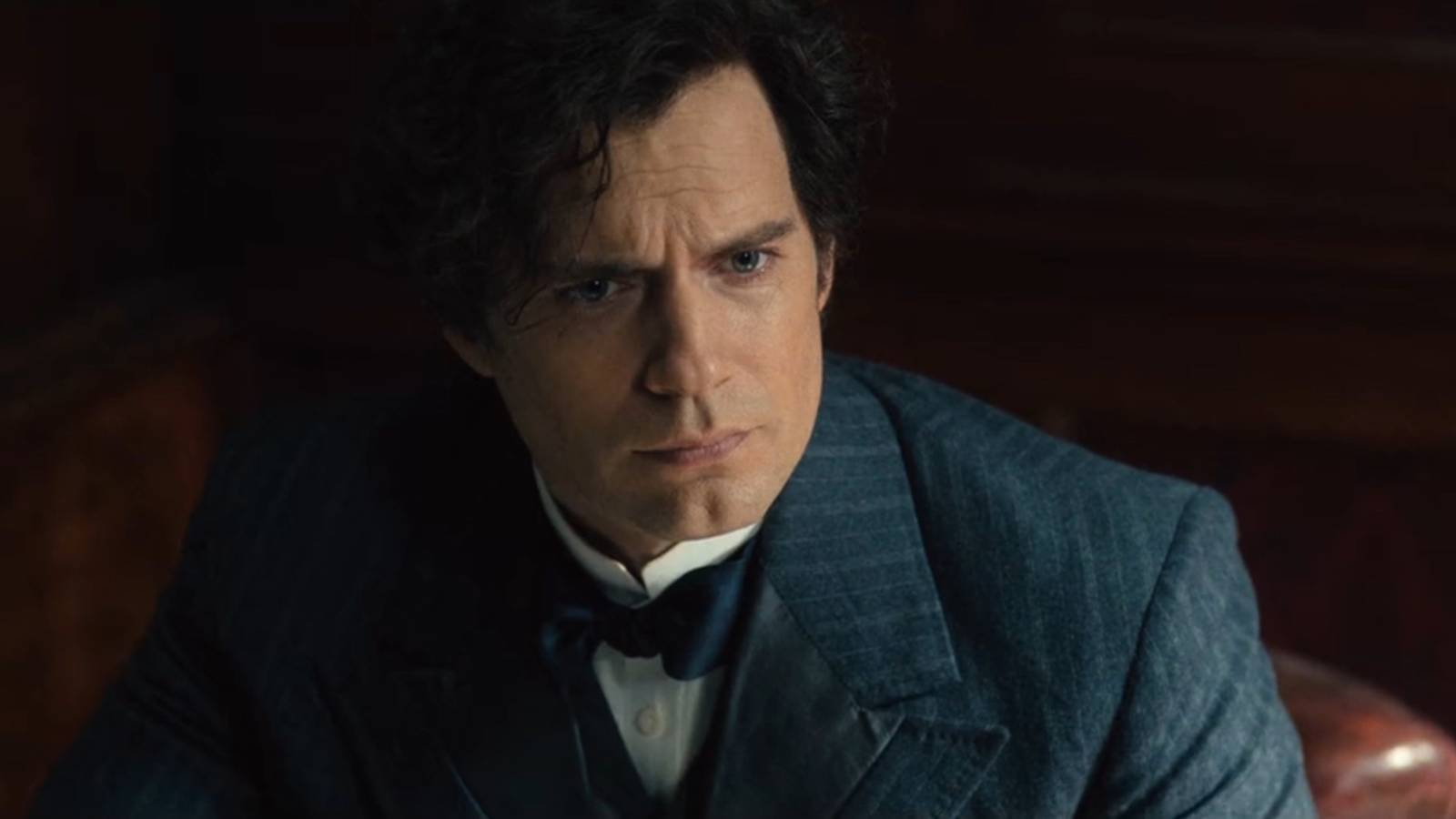 Henry Cavill's Sherlock Holmes looking up at Enola while seated at his desk