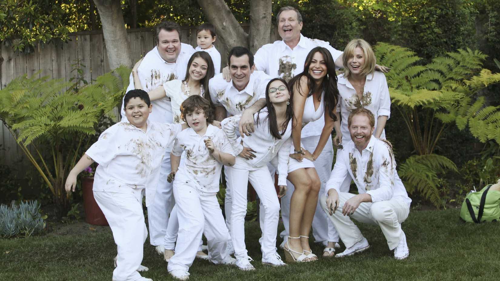 The cast of Modern Family posing for a family portrait dressed in white clothes