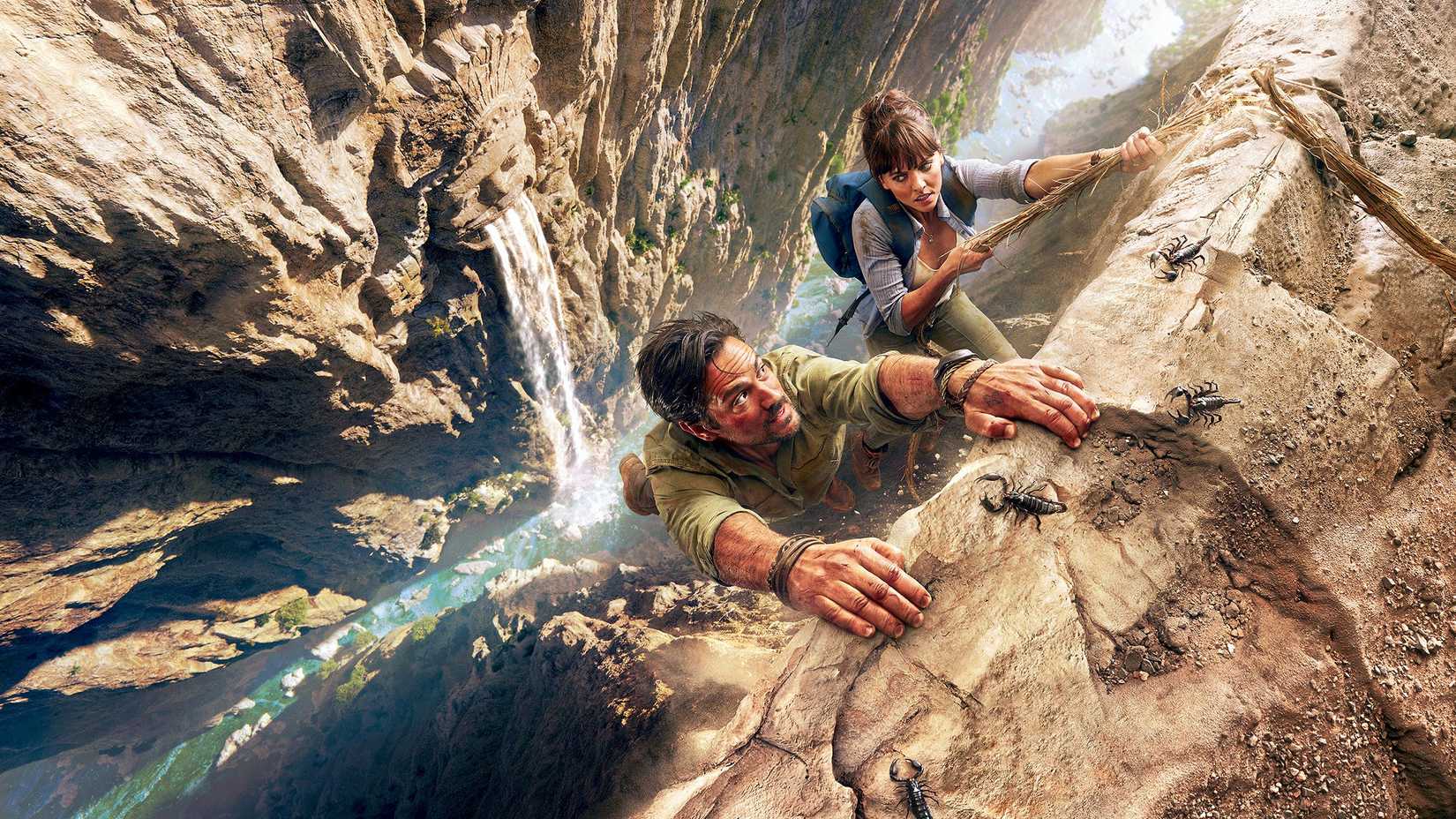 Ulysses Hooten (Michael Landes) and Lady Alexandra Lindo-Parker (Ophelia Lovibond) hanging on to a cliff in Hooten & the Lady.