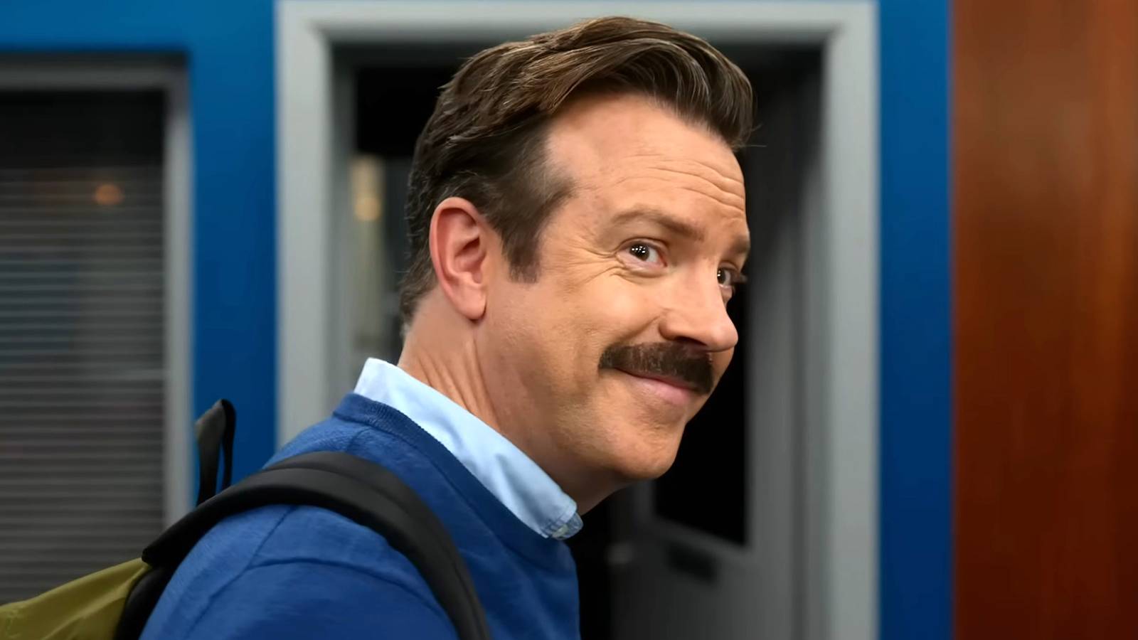 Jason Sudeikis' Ted smiling while looking over his shoulder in Ted Lasso season 4