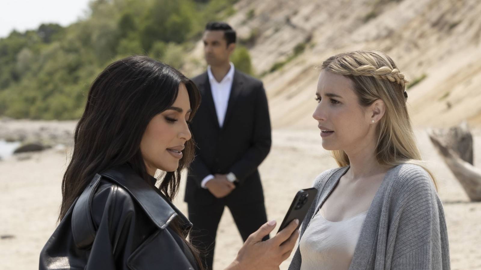 Kim Kardashian and Emma Roberts stand on a beach with a bodyguard between them in American Horror Story Delicate