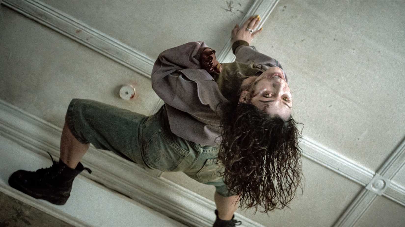 Luciane Buchanan's Thya on the ceiling looking below her in Evil Dead Burn