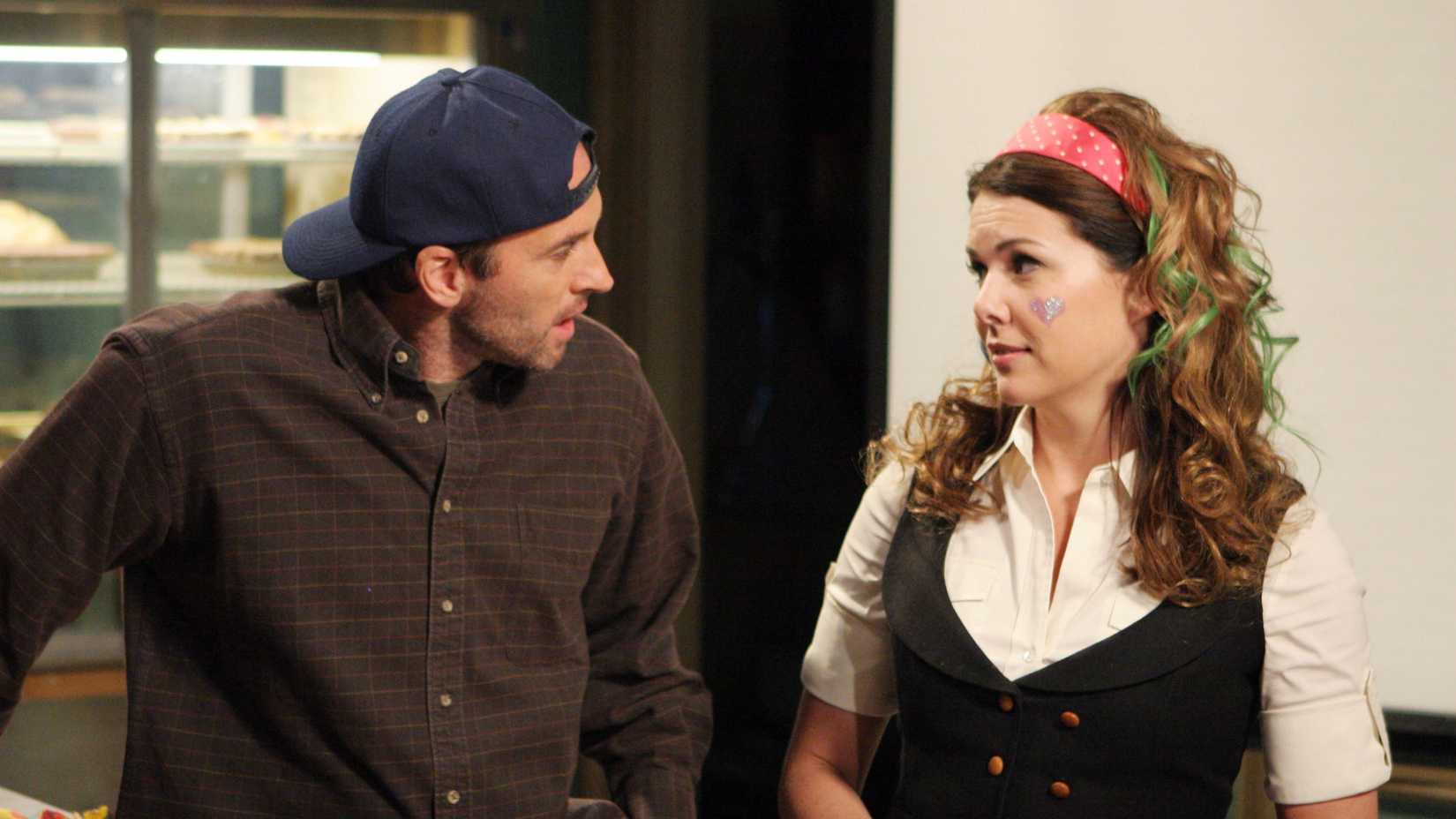 Luke looks at Lorelai who has a glitter heart on her cheek and green hair extensions in Gilmore Girls season 6