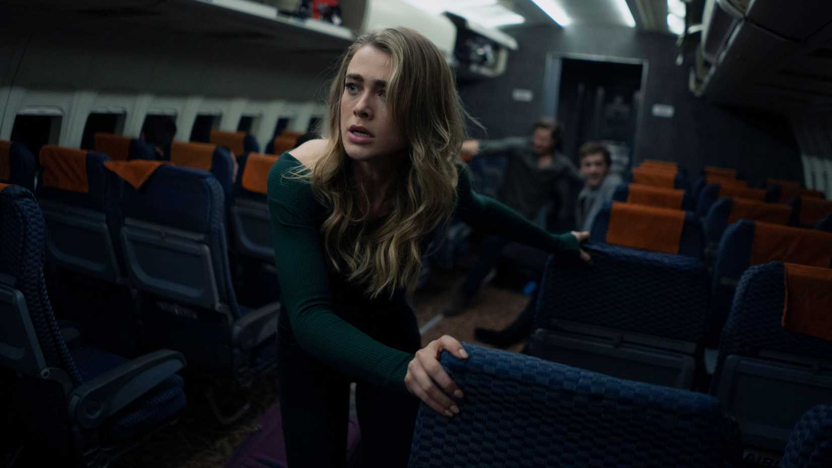 Melissa Roxburgh as Michaela Stone struggling to climb through a plane aisle in Manifest.