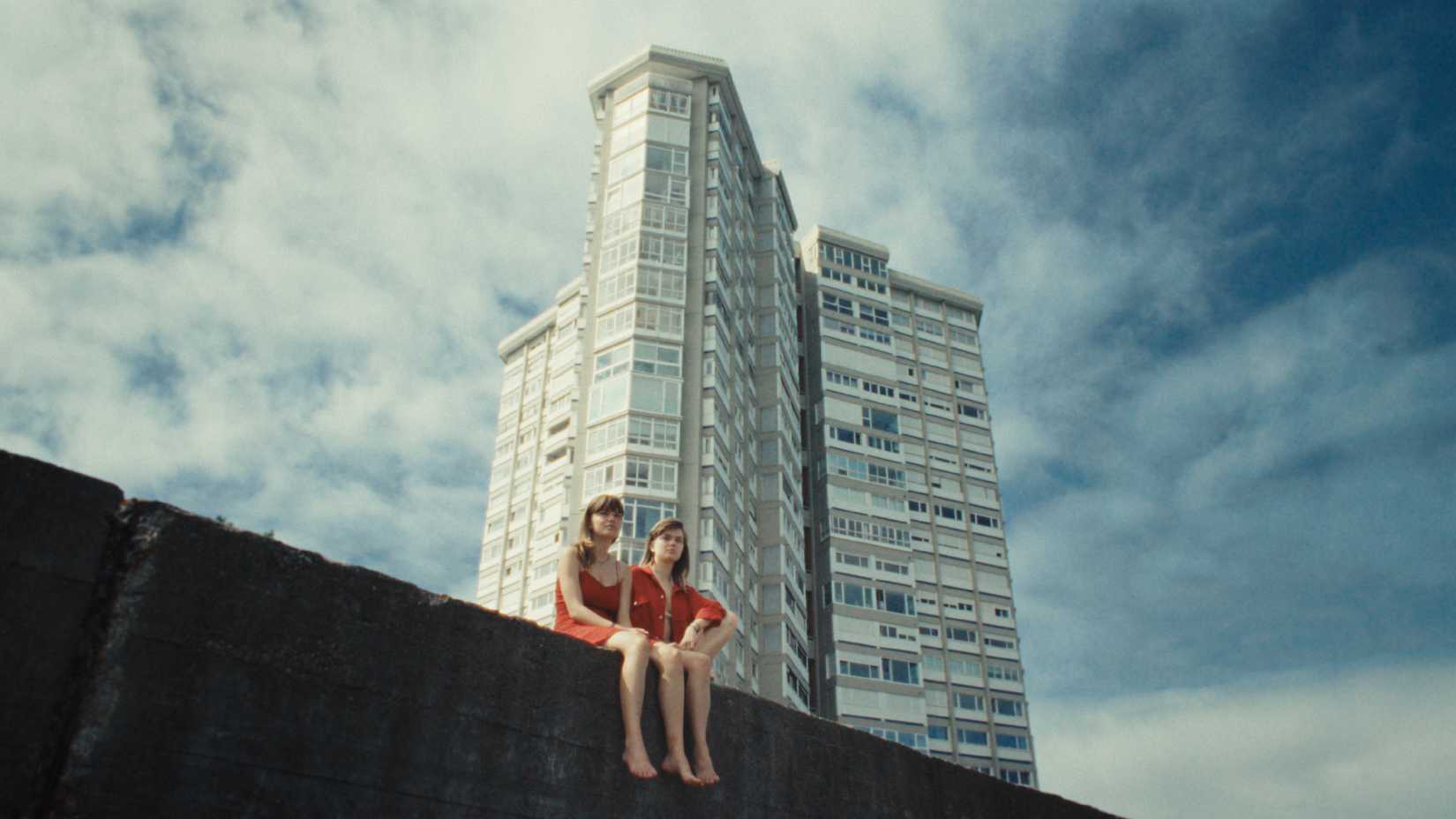 Marina y otra mujer vestida del mismo color contra un edificio de apartamentos