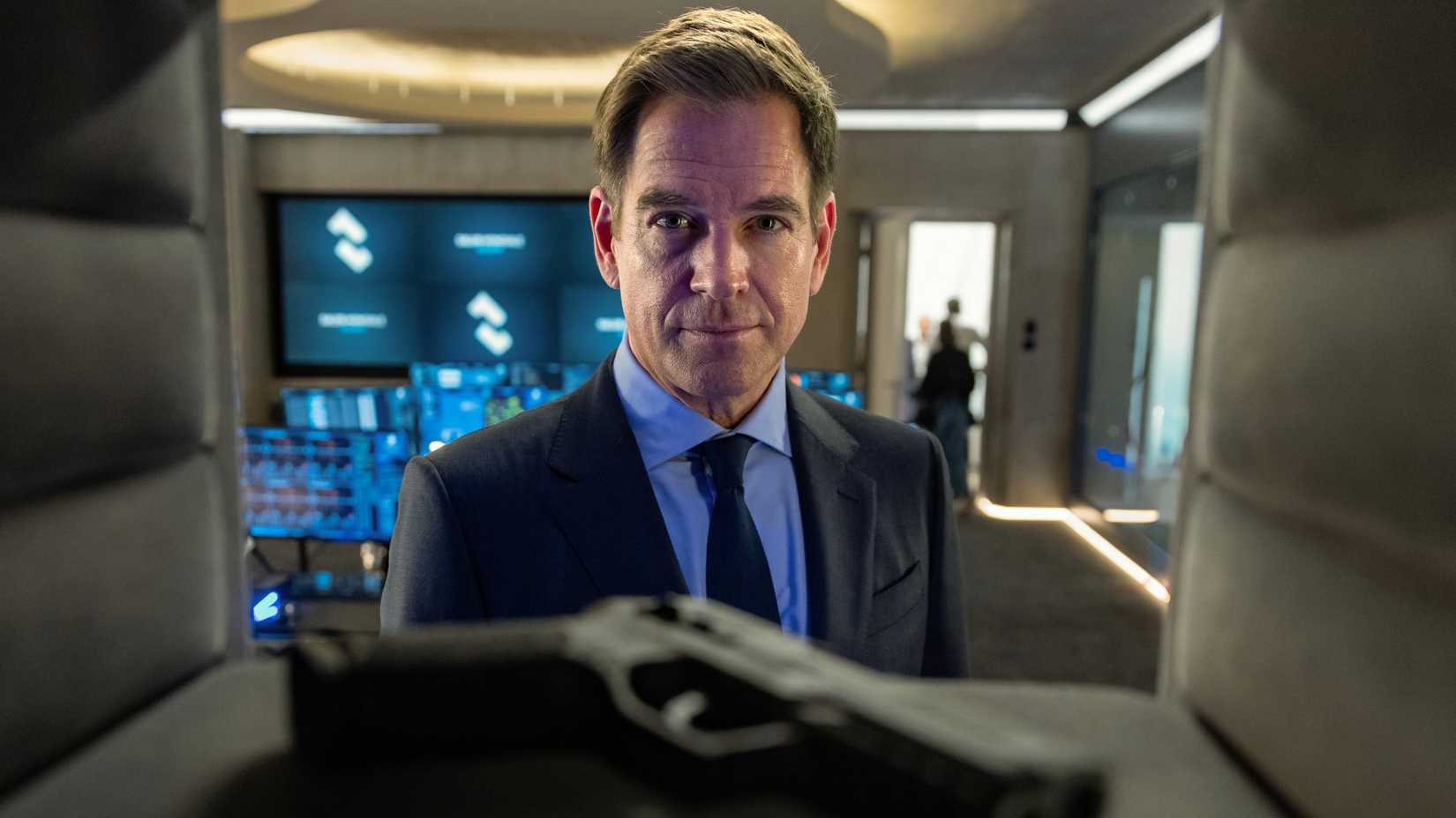 Michael Weatherly's Tony smiles while looking at a gun in a safe from NCIS Tony & Ziva