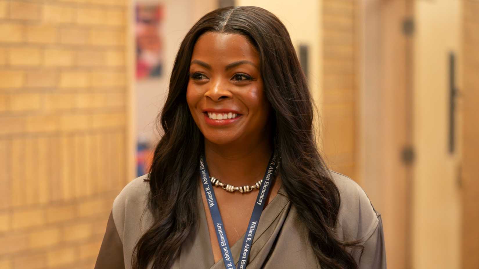 Ava (Janelle James) smiling in the school hall in Abbott Elementary season 5