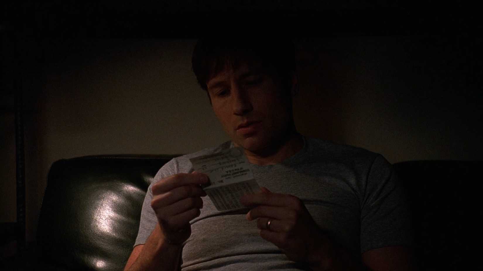 Mulder holds up a piece of paper with a wedding ring on his finger in The X-Files