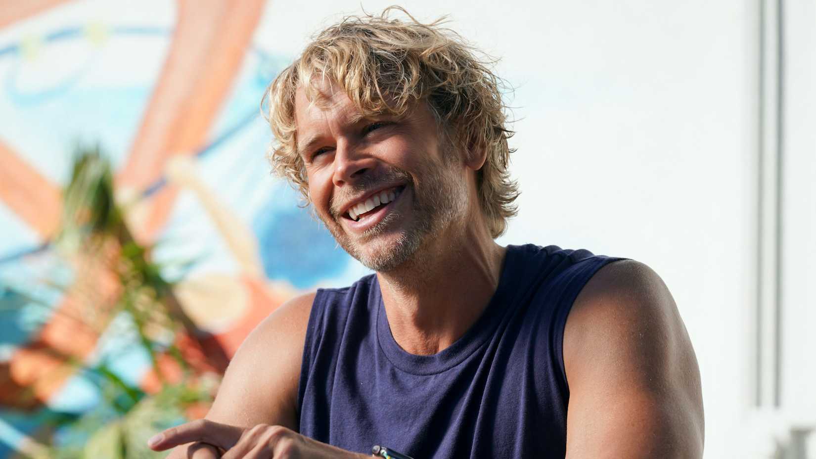 Marty Deeks smiling while wearing dark blue tank top