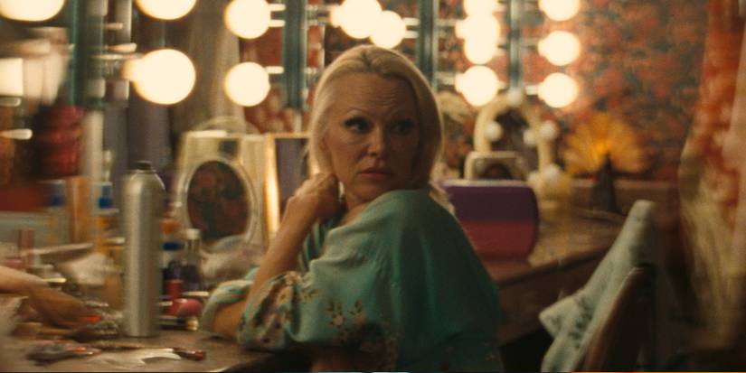 Pamela Anderson in The Last Showgirl sits in front of a mirror and looks over her shoulder