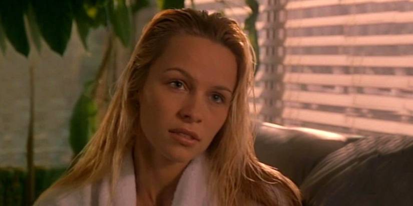 Pamela Anderson sits on a couch in Snapdragon