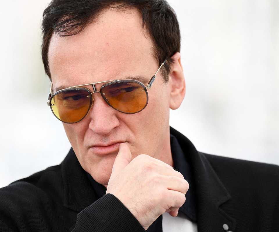 Quentin Tarantino posing with his hand on his chin at the Once Upon a Time in Hollywood Cannes red carpet