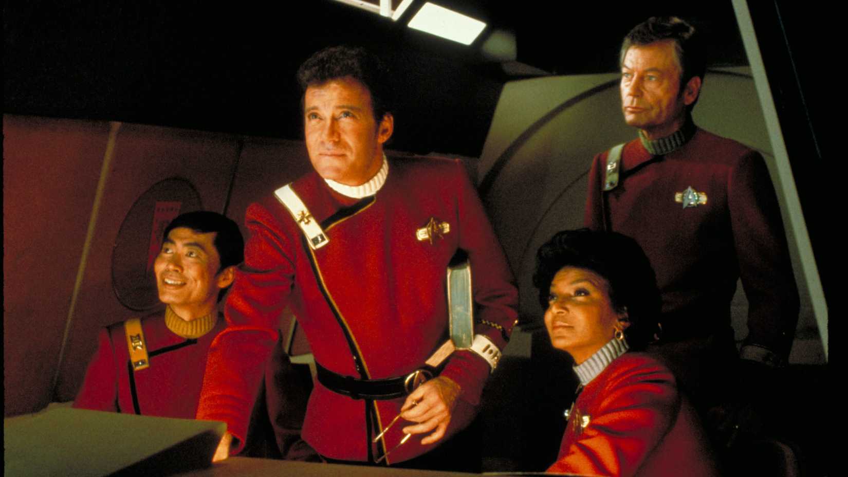 Kirk, Sulu, Uhura, and McCoy positioned by a ship console