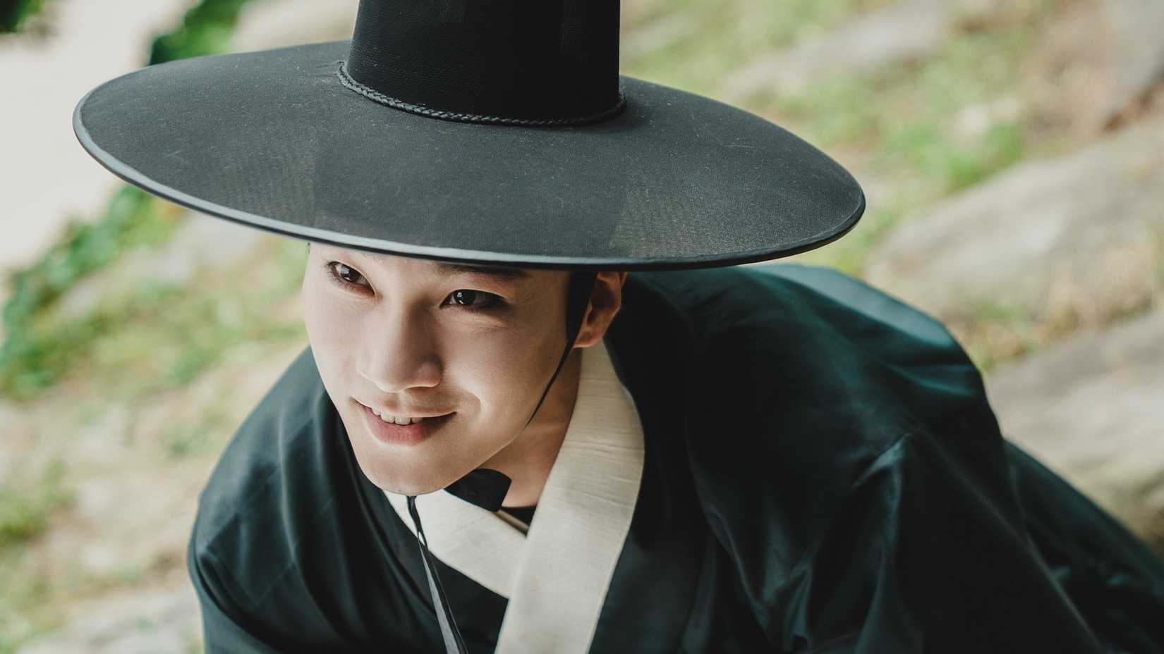 A man in Joseon Era clothes grinning darkly in The East Palace.