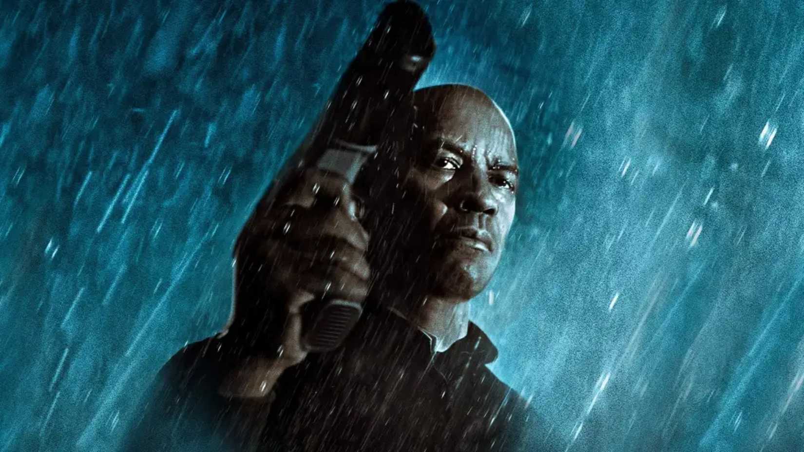 Denzel Washington holds a gun in the rain in The Equalizer