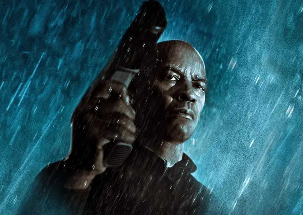 Denzel Washington holds a gun in the rain in The Equalizer