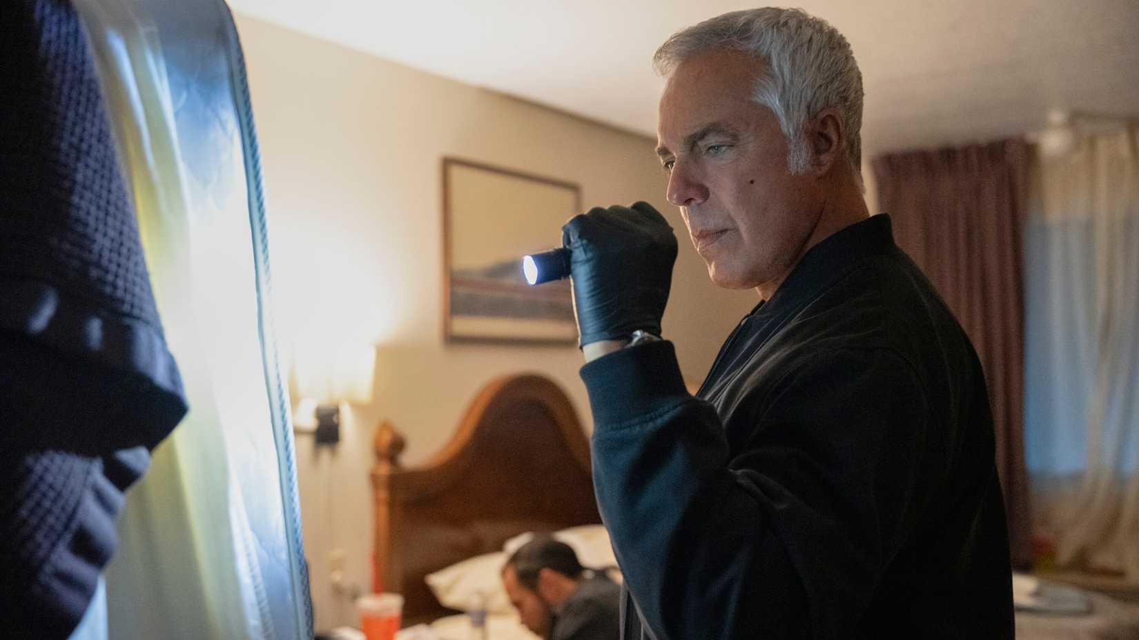 Titus Welliver's Bosch pointing a flashlight toward an object in Bosch: Legacy season 3