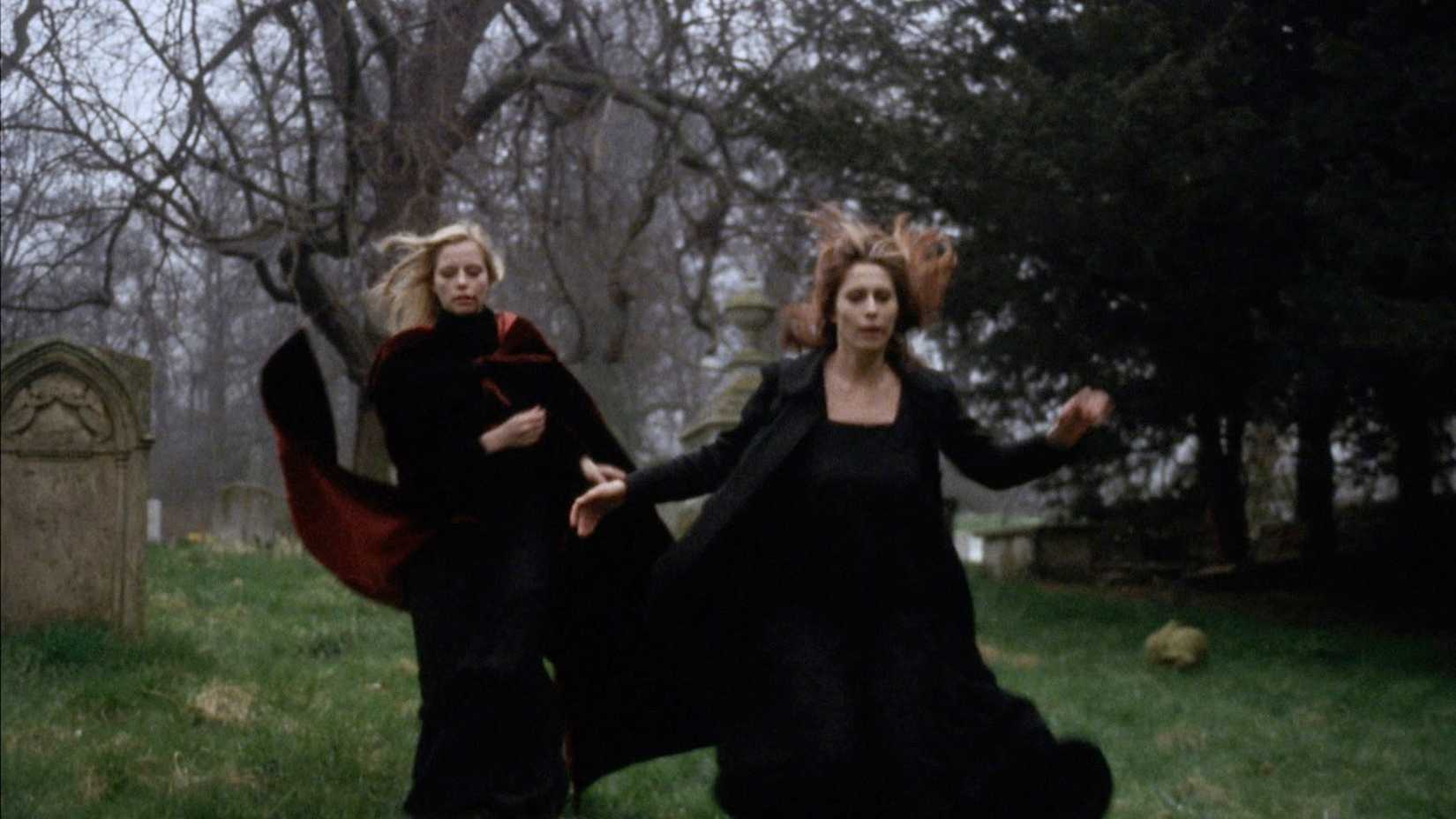 Two women in black run through a graveyard in Vampyres (1974)