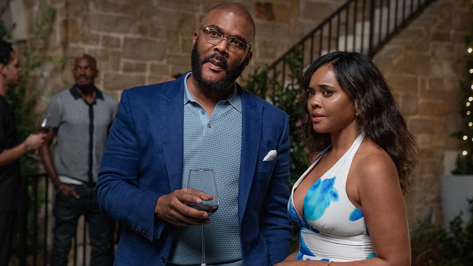 Tyler Perry's Terry and Sharon Leal's Diane looking concerned at something while holding wine glasses in Why Did I Get Married Again