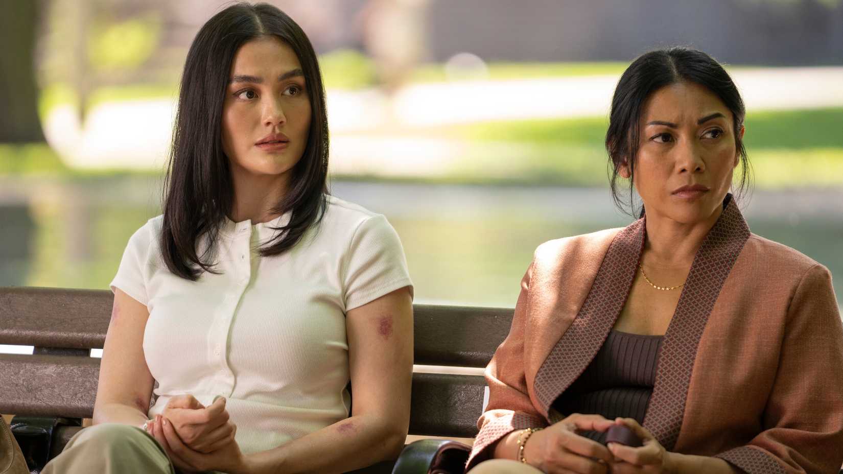 Agnez Mo as Lilo Hoth and Anggun as Amisha Hoth sitting on a bench in Reacher season 4