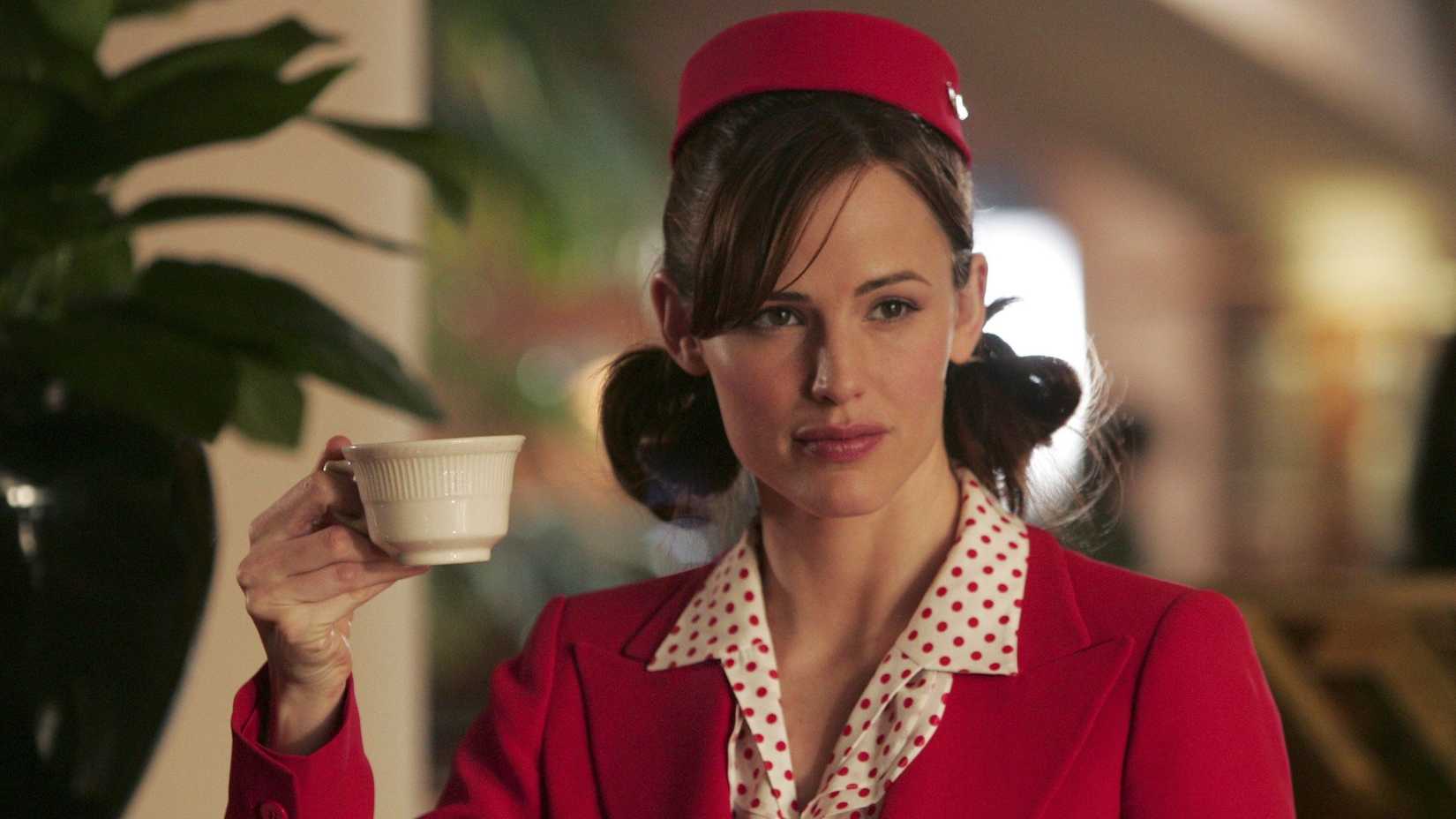 Jennifer Garner as Sydney Bristow wearing a red outfit and holding up a coffee cup in Alias.