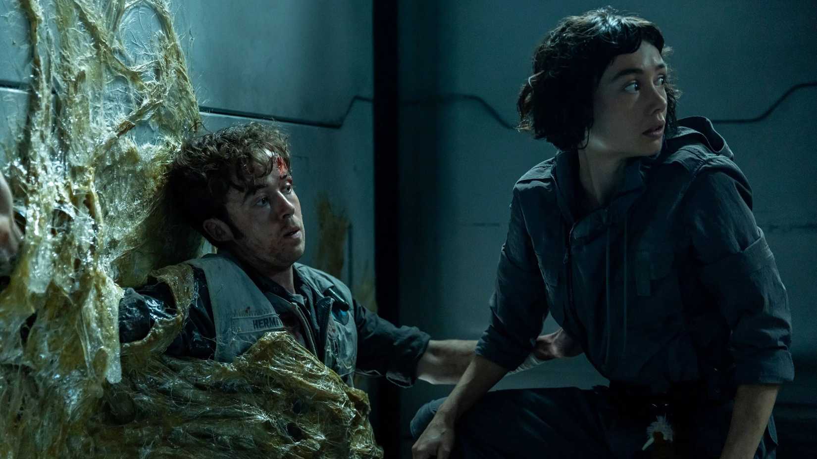 Joe DiMaggio Hermit (Alex Lawther) trapped in a Xenomorph cocoon and Wendy (Sydney Chandler) looking over her shoulder in Alien: Earth.