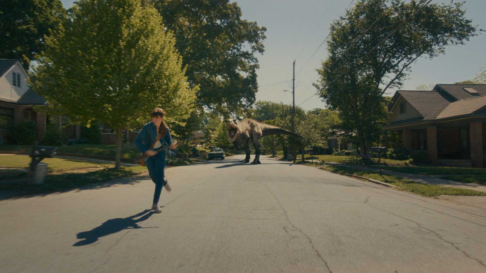 Anne Hathaway As Denise Running Away From A Dinosaur On A Suburban Street In The End Of Oak Street