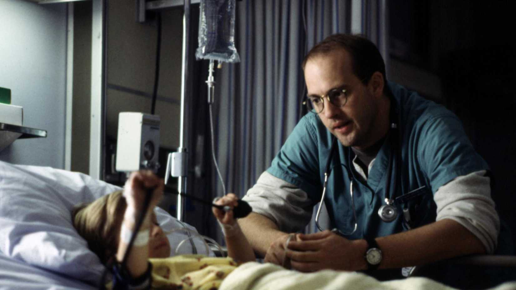 Anthony Edwards' Mark looking over a child patient in a bed in ER season 1
