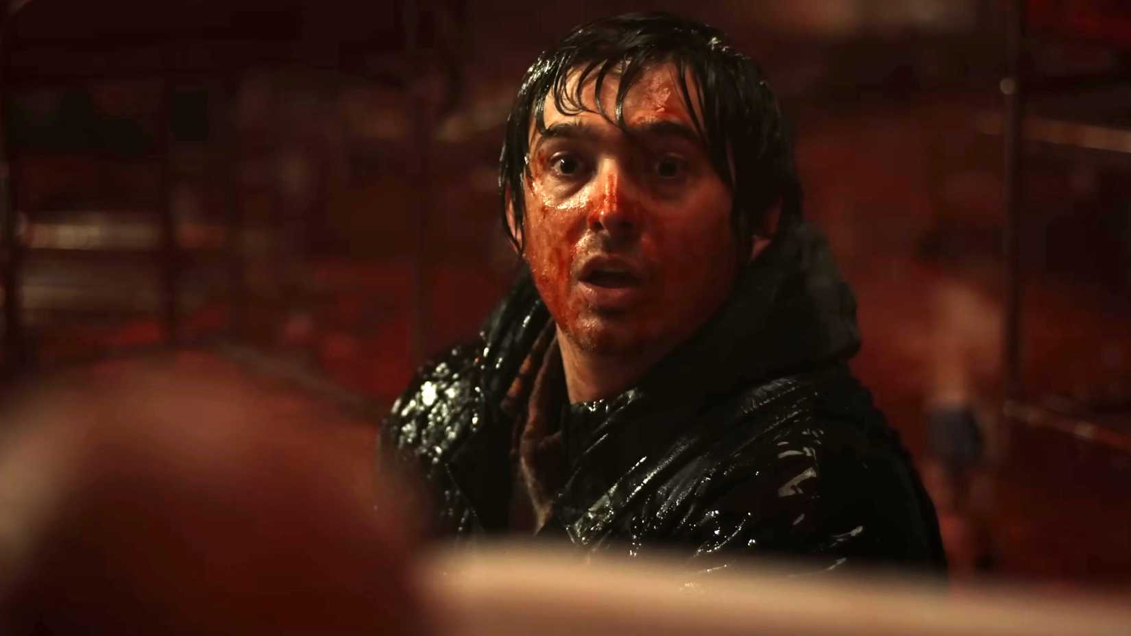 Austin Abrams' Bryan covered in blood looking shocked at an unseen creature in Resident Evil