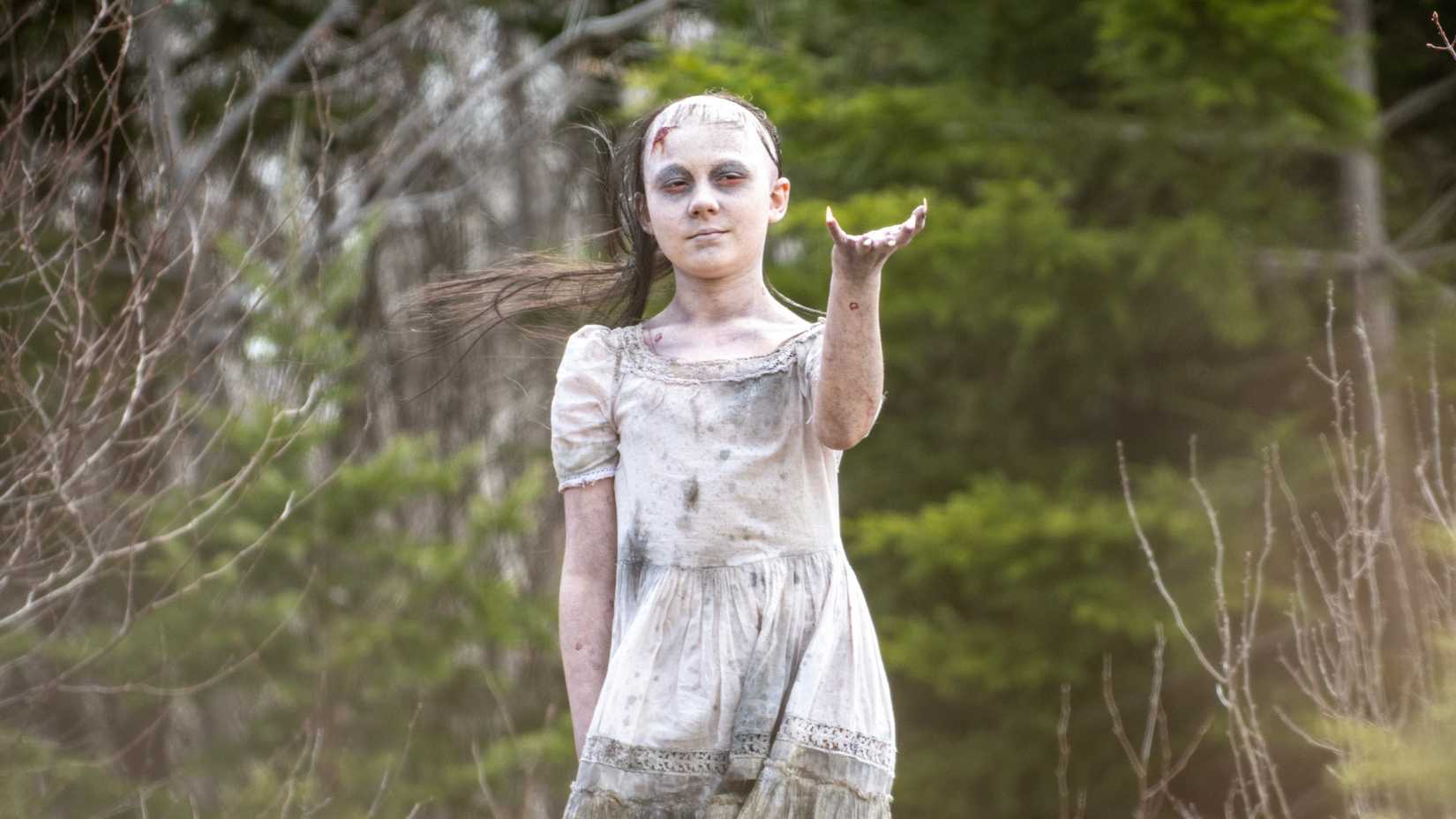 A girl in white raising her hand in MGM+’s From