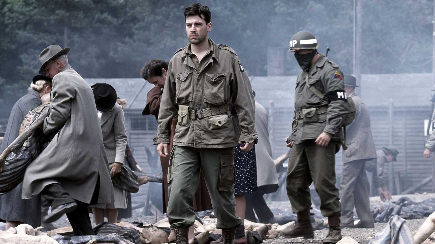 Nixon (Ron Livingston) walking through the concentration camp while villagers move bodies in Band of Brothers.